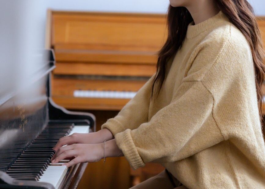 asian female musician playing piano in classroom